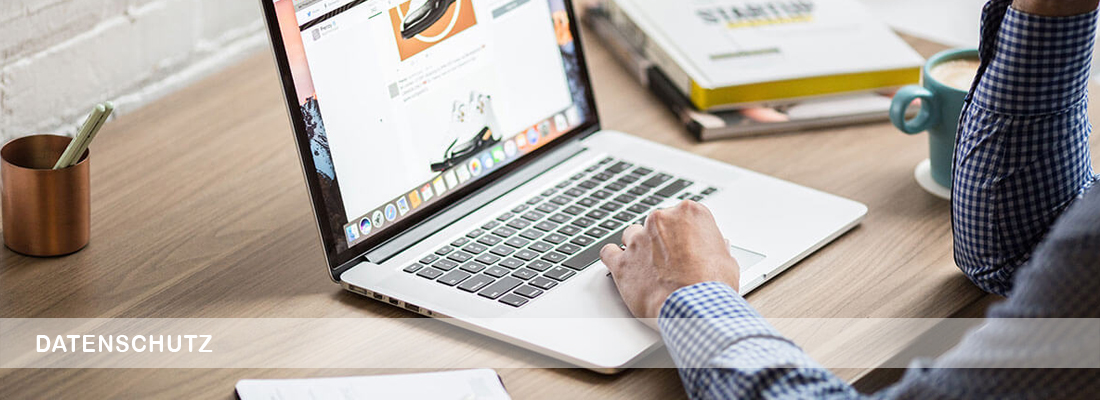 Schreibender Mensch am Laptop an einem Tisch sitzend